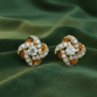 Planet Genesis - The Eternal Knot Diamond Earrings with spiral motifs, pavé diamond setting, shown on lustrous green satin fabric background. - IGI-Certified Lab-Grown Diamonds