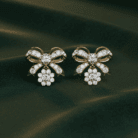 Planet Genesis - Gold bow-shaped earrings with white diamonds and diamond clusters, filigree design, displayed on dark green velvet. - IGI-Certified Lab-Grown Diamonds
