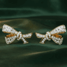 Planet Genesis - Gold ribbon bow earrings featuring pavé diamonds, styled on emerald green satin for a premium, elegant jewellery presentation. - IGI-Certified Lab-Grown Diamonds